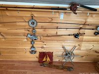 Full view of mounted fishing rods on wooden wall, several rods visible, nautical decorations hanging and placed below.