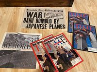 Photo showing Honolulu Star-Bulletin Extra newspaper from December 8, 1941 with large headline on Pearl Harbor attack and several Time magazine issues including 9/11 coverage.