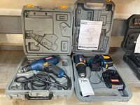 Lot overview showing two Ryobi drills in gray carrying cases: one corded drill with attached power cord and one cordless drill with charger and manual.