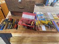 Wide shot of all screwdrivers and tools laid out on a wooden table, including a wooden box behind.