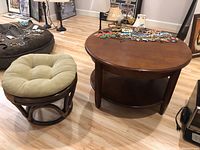 Photo showing the round table with jewelry displayed on top and bamboo style stool with cushion next to it