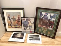 Wide photo showing all three framed Rockwell prints and two photography books placed on the floor against a wall