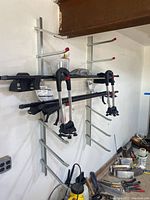 Metal wall mounted storage rack with multiple arms holding items, photographed from an angle showing two vertical supports and arms with red tips.
