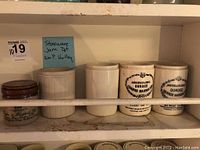 Shelf with five ceramic stoneware jars including three labeled 'James Keiller & Son Ltd Dundee Orange Marmalade', one Wm. P. Hartley jam pot, and one Pickton Whitfield English Blue Stilton cheese jar.
