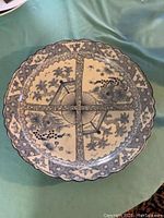 Top view of large scalloped round ceramic charger with blue and white Imari style floral decoration and crosshatch band divided quadrants.
