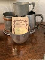 Four pewter cups stacked showing the variety of styles and a label indicating one cup is by Stieff.