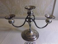 Front and side angle of silver three-arm candelabra on table