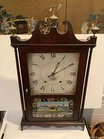 Front view of Seth Thomas mantel clock, showing wood case, clock face with Roman numerals, and reverse painted glass panel depicting buildings.