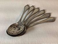 Six Towle sterling silver teaspoons stacked with bowls visible, showing heavy tarnish spots.