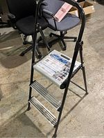 Full view of the 3 step ladder showing the black frame, three metal steps and curved top handrail.