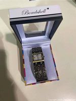 View of the Bombshell watch in its original box showing the decorative band and rectangular face.