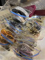 Overhead shot of assorted jewelry pieces sorted in ziplock bags showing bead necklaces, bracelets, earrings and watch components