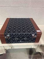 Closed monogrammed Carl Weill carrying case with metal latches and handle