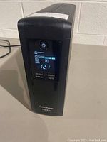 Angled front view showing LCD display reading 121V, power button, select/display and enter/mute buttons, CyberPower 1500VA label.