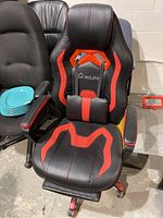Front view of the black and red EcLife gaming chair showing its padded seat and backrest with lumbar support pillow and headrest pillow, plus adjustable armrests.