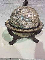 Closed view of the antique style wooden globe showing vintage map and wooden stand