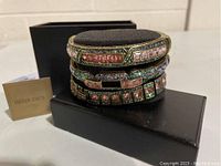 Three-piece bracelet/bangle set on black cushion with box and Heidi Daus tag visible