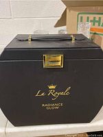 Closed black La Royale Radiance Glow box with gold logo and latch