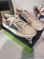 Side view of left and right sneakers on original Sam Edelman box, showing pastel floral print and beige toe caps