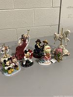Lot containing Disney figurines, an angel statue, vintage-style children figurines, carousel horse, and a decorative egg.