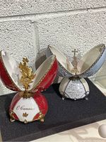 Both red/white and blue/white musical egg-shaped trinket boxes displayed open, showing interiors and gold accents