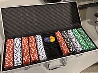 Open metal carrying case showing full poker chip set arranged in rows with dealer chips