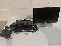 QSEE DVR system with eight security cameras and HP monitor on white table against white brick wall.