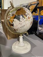 Photo of the globe showing the Indian Ocean, Africa, and Asia with parts of the brass arm and white base visible.