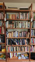 Full view of wooden bookshelf with seven shelves filled with various books