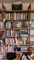 Full view of 5 wooden shelves packed with assorted books including religious and non-fiction topics.