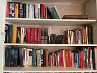 Three shelves of numerous vintage and themed books packed closely together, some with visible titles and different sizes