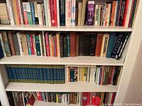 Photo of bottom four shelves of books showing various titles covering gardening, encyclopedias, world books, and assorted subjects.