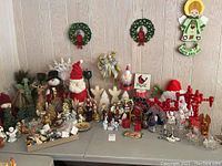 Wide view of Christmas lot showing figurines, candle holders, wreaths, and assorted decorations on folding tables.