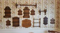 Wide view of all 12 wooden shelves mounted on wall showing different designs and sizes for spoon display.