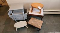 Overall photo showing all five pieces: four stools of various sizes and a light blue wooden magazine stand.