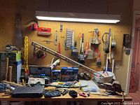 Wide view of workbench with toolbox, socket sets, hand tools, level, and ear protection on pegboard