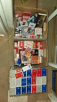 Three boxes filled with multiple decks of playing cards, many airline branded such as TWA, United, Continental, Qantas, American, Delta, Western Airlines, SAS. Mix of sealed and unsealed decks.