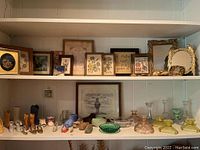 Two shelves with various miniature shoes, framed pictures, glass candlesticks and bowls.