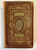 Front cover of the 19th century bound Holy Bible with embossed gold and green lettering and design on brown leather.
