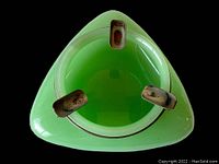Top-down view of pale green jadeite glass ashtray showing three evenly spaced metal cigarette rests around rim.