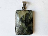 Front view of the green rutilated quartz pendant showing textures and inclusions within the stone.