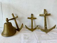Lot layout showing one bell and three brass anchors arranged left to right against white background.