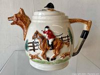 Front view showing the fox head spout and the hunting scene relief with horse rider and dogs on teapot body.