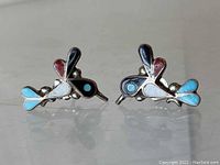 Front view of the pair of sterling silver hummingbird earrings showcasing inlaid turquoise, red, black, and white stones