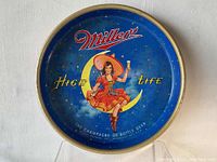 Front of the vintage round metal beer tray featuring Miller High Life logo and cowgirl illustration on blue background.