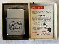 Zippo lighter in original box with usage leaflet visible inside box lid.