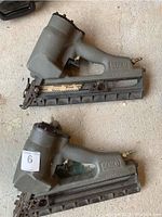 Two gray Senco SN325 framing nailers side by side on concrete