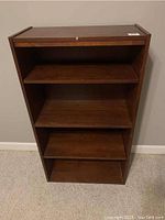 Front view of wooden bookshelf showing all three shelves and flat top, dark walnut finish.