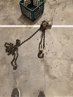 Full view of chain hoist laid out on floor with lever arm extended and chain visible.