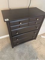 Front view of the brown 4-drawer chest of drawers showing decorative knobs and overall condition